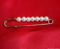 Full view of gold-tone safety pin brooch with pearls