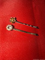 Two crystal embellished bobby pins on red background