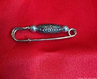 Front view of silver-tone safety pin brooch on red fabric