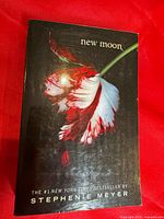 Front cover of New Moon paperback showing title, author, and flower artwork