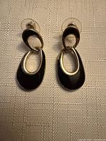 Front view of both earrings showing black enamel and gold-tone borders