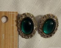 Front view showing green cabochons, gold-tone lattice border, ruler for size reference