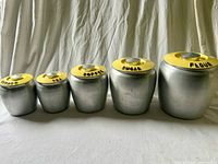 Front view of all five Kromex aluminum canisters with lids on