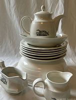 Stacked view of plates, teapot, small pitchers and serving bowl