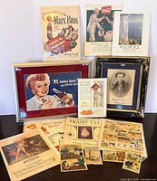 Group shot of all items including framed ads, posters, sheet music, magazine ads