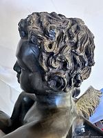 side view of bronze cherub head, showing hair detail