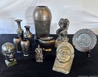 Group shot of all metal figurines, vases, plaques and stand