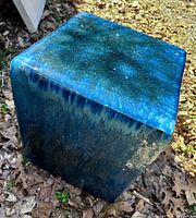 Three-quarter corner view of glazed ceramic stool showing overall form and color