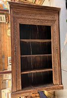 Front view of carved teak bookcase showing shelves and detailed carving