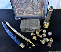 Group shot of all items: thangka, saber with scabbard, tin box, brass base, doorknobs