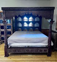 Full view of carved canopy bed showing headboard arches, roof and pillars