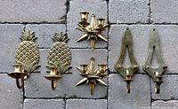 All six brass sconces grouped: pineapple pair, starburst pair, shield pair