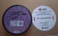 Signed purple Hockey Fights Cancer puck and certificate of authenticity displayed on flat surface