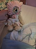 Front view of teddy bear wearing pink bonnet and floral dress