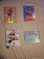 All four Jack Hughes cards laid out: orange foil Allure Flashy, blue foil insert, white-border base style, turquoise foil insert