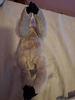 Full body view of plush sloth lying face-down, arms extended