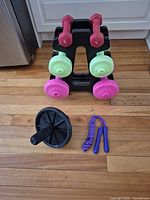 Front view of rack holding six dumbbells with ab wheel and jump rope in foreground