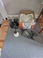 Assorted light fixtures on floor including pendant, sconce, lantern and glass bowl