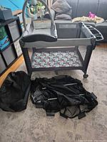 Playard assembled with mattress pad, carry bag and folded frame on floor