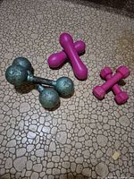 Group of all dumbbells: teal 7 lb pair, pink X-shaped 2 lb, pink GoZone 2 lb
