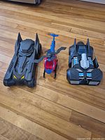 Overall view of two black cars and red/blue helicopter on floor