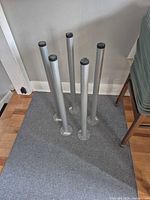 Five silver metal IKEA ADILS table legs standing upright showing overall appearance