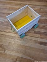 Top view showing natural wood cart, yellow base, green rope handle