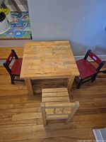 Square wood kids table with two red Little Tikes chairs and one natural chair