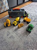 All six plastic construction vehicles on rug