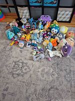 Group shot of all 49 mixed plush animals arranged on rug