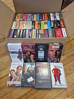 Open box showing two rows of VHS tapes and seven titles displayed in front