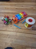 Group shot of all three toys: wooden shape sorter, tiger pull-along xylophone, spinning egg toy