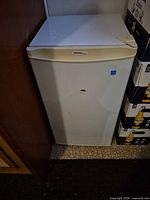 Closed front view showing Danby logo, integrated handle, off-white finish, dent, size context