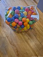 Bag filled with multicolor plastic balls on wooden floor