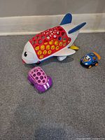 Oball-style perforated plastic airplane, purple perforated car, blue character car on carpet