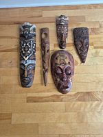 All five wooden masks laid out on floor