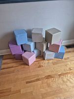 Front view of 14 pastel vinyl foam cube blocks stacked against wall