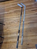 Two hockey sticks full length on floor