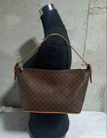 Front view of brown coated canvas shoulder bag showing Macadam pattern, tan leather strap and trim