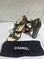 Front quarter view of both Chanel green patent leather sandals with CHANEL cloth visible