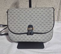 Front view of Gucci Micro GG shoulder bag on stand showing monogram pattern and clasp
