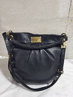 Front view of black leather Marc Jacobs Hillier Hobo with gold hardware and long strap