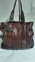 Front view of brown leather Miu Miu tote with flower detail and dual handles