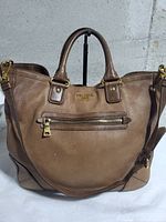 Front view showing logo, front zip pocket, handles and detachable strap