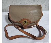 Front view showing pebbled leather, tan trim, brass turn-lock, adjustable strap