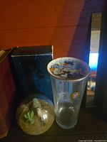 Group shot showing blue box, glass paperweight, beer glass and saucer stacked on top