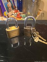 Both padlocks standing upright on black surface