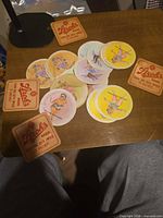 Group of square Stroh's coasters and round pin-up coasters spread on table