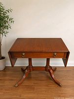 Full view of drop-leaf mahogany table showing drawer and double pedestal base