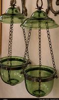 Pair of emerald green glass hanging planters suspended by chains